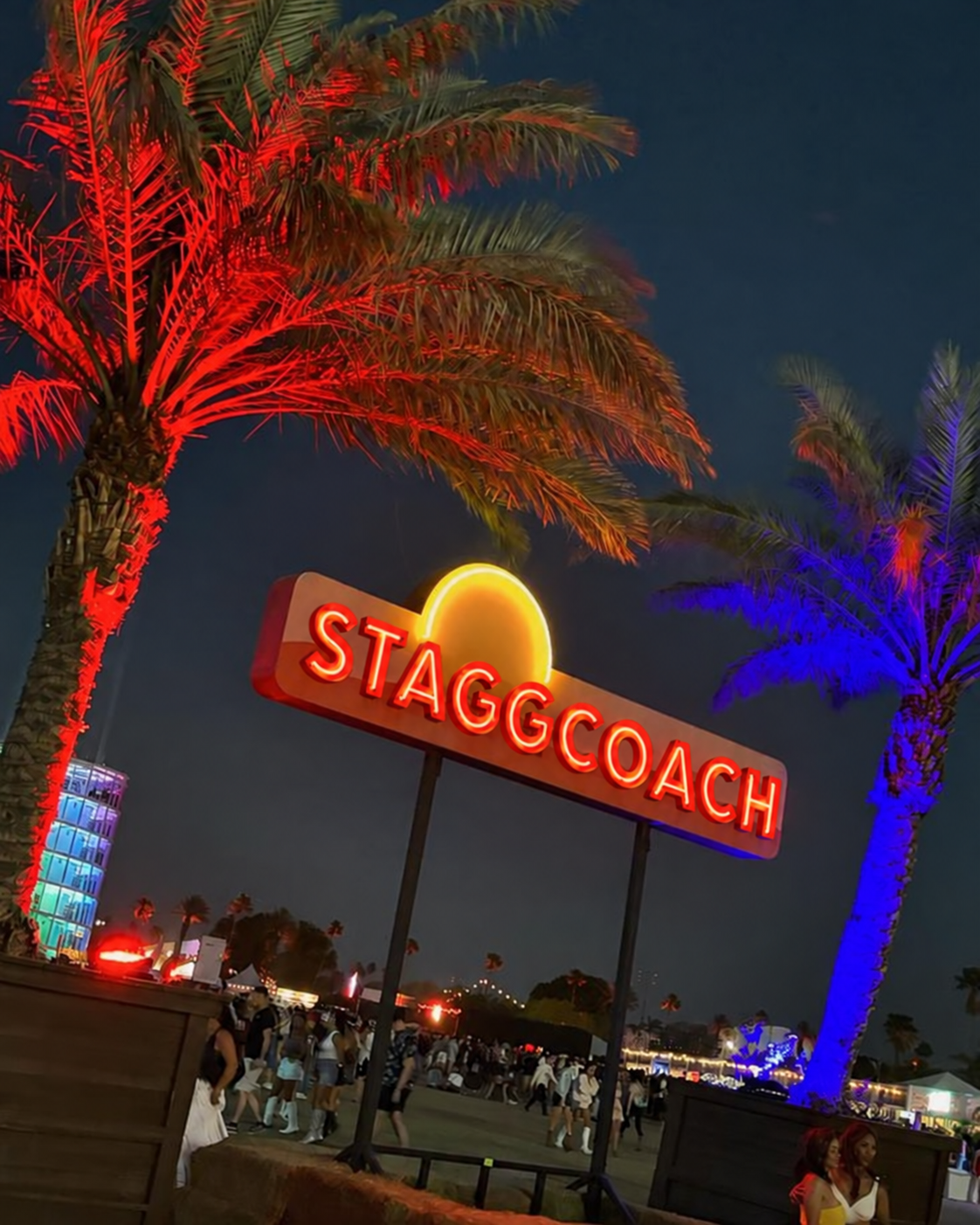 The illuminated Staggcoach entrance sign beneath colorful palm trees